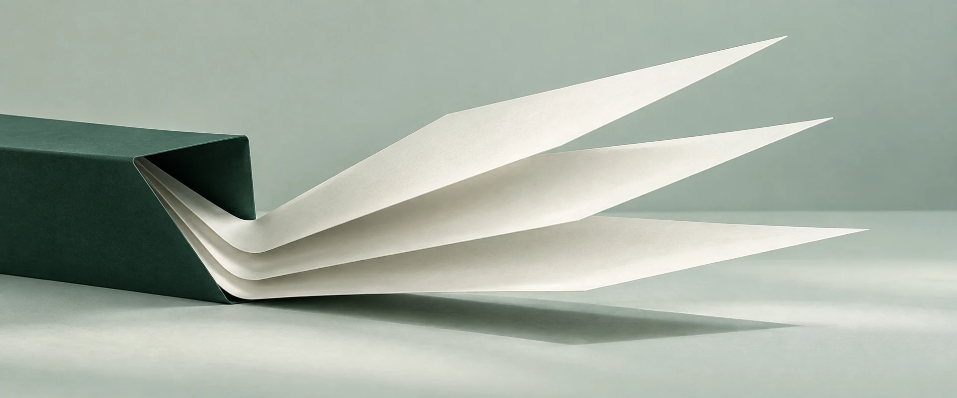 Ivory folded planes meet along a shared crease on a deep-green and sage surface.